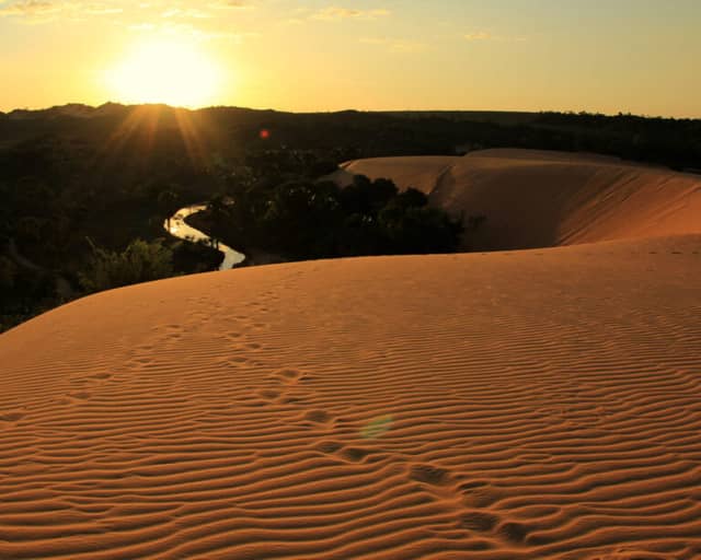Golden sand dunes at sunset with a winding river in Jalapão State Park, Brazil