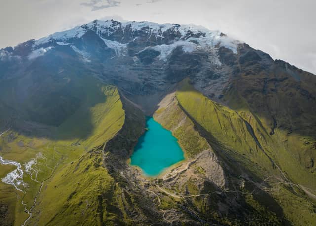 Aerial view of turquoise Humantay Lake in a green glacial valley beneath the snow-capped Salkantay range in the Peruvian Andes