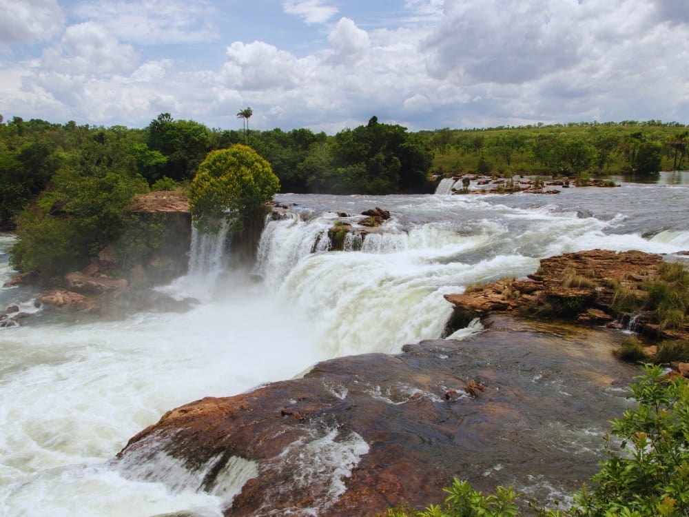 De krachtige hoefijzervormige Velha Waterval die over rotsachtige kliffen stroomt langs de goed bewaarde Novo Rivier.