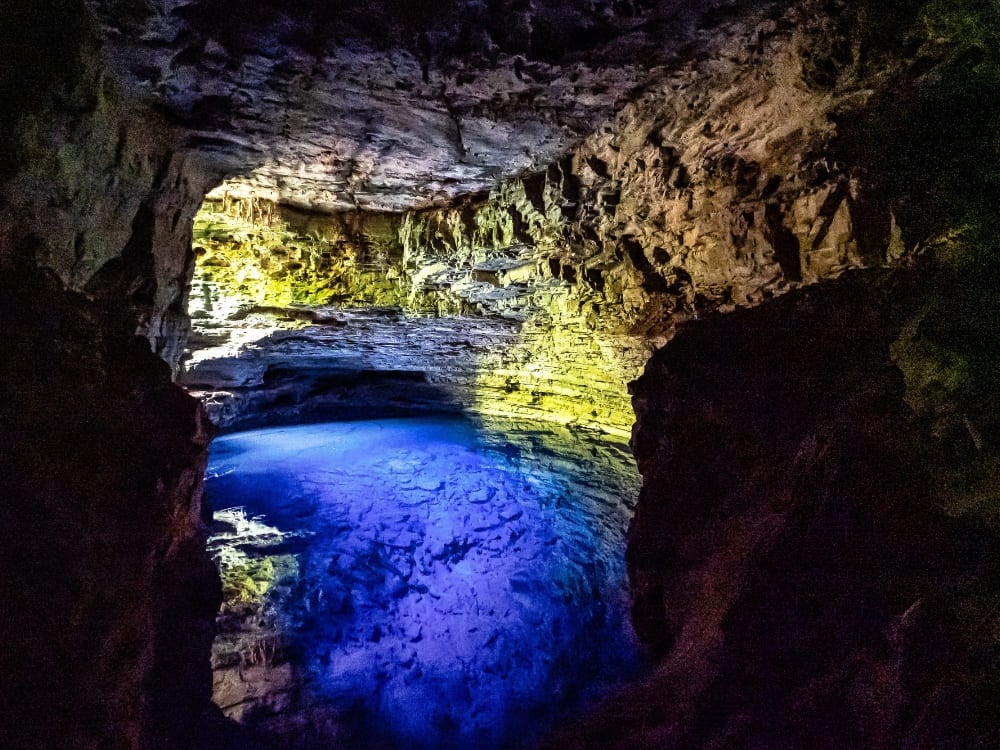 Um raio de sol brilhante ilumina a água azul e cristalina dentro da caverna subterrânea de calcário do Poço Encantado.