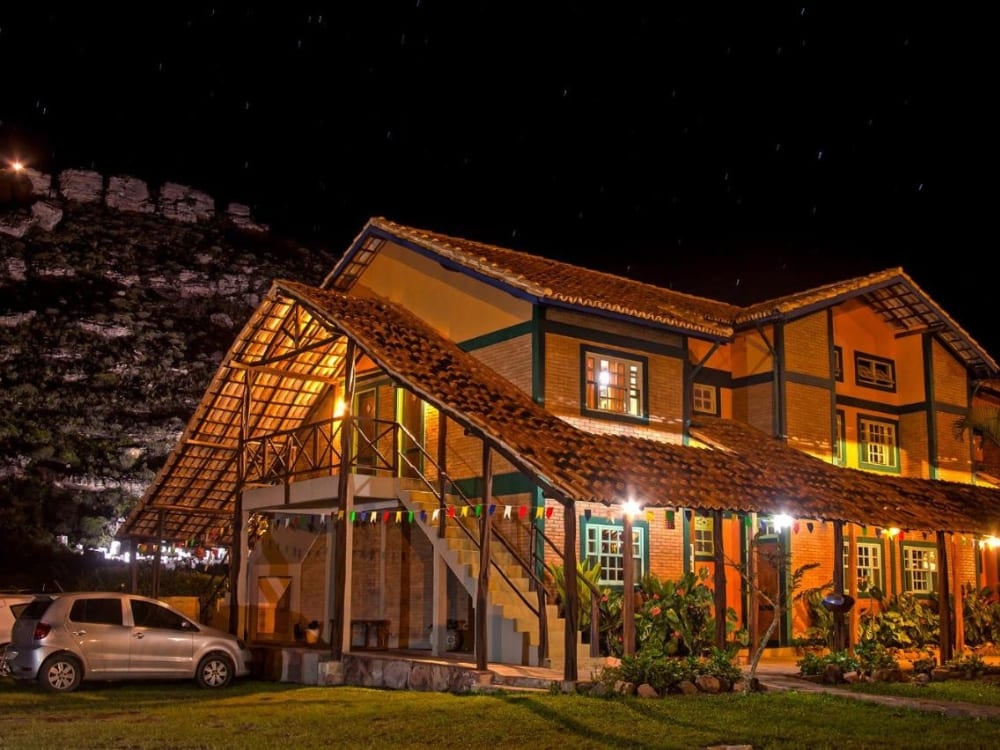 Exterior rústico da Pousada Monte Azul em Mucugê iluminada à noite sob um céu escuro.