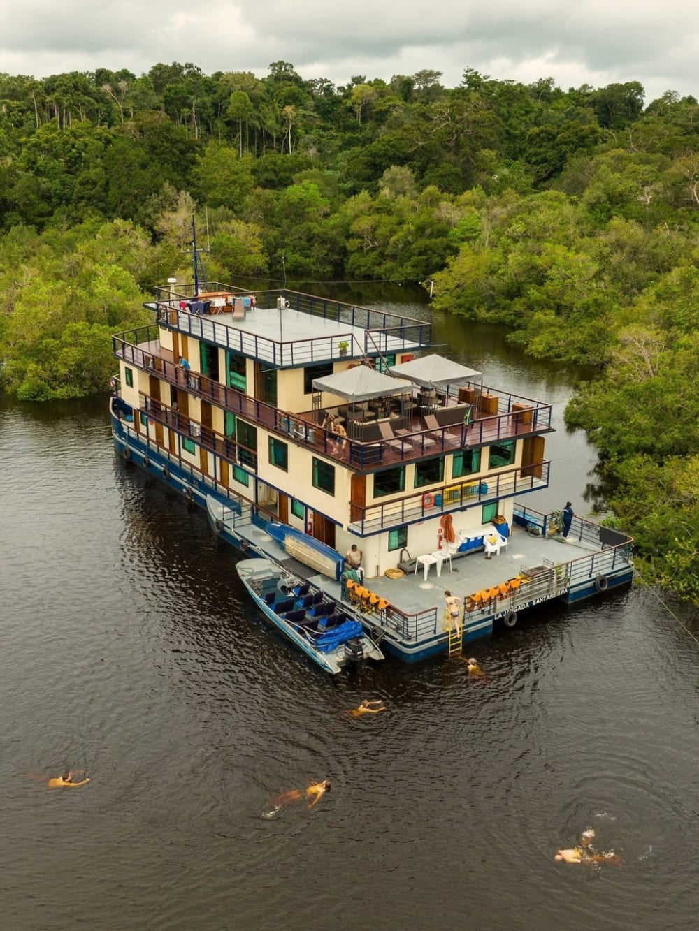 Vue aérienne du bateau fluvial La Jangada amarré près de la jungle, mettant en évidence son vaste pont supérieur et sa proximité avec la nature amazonienne.