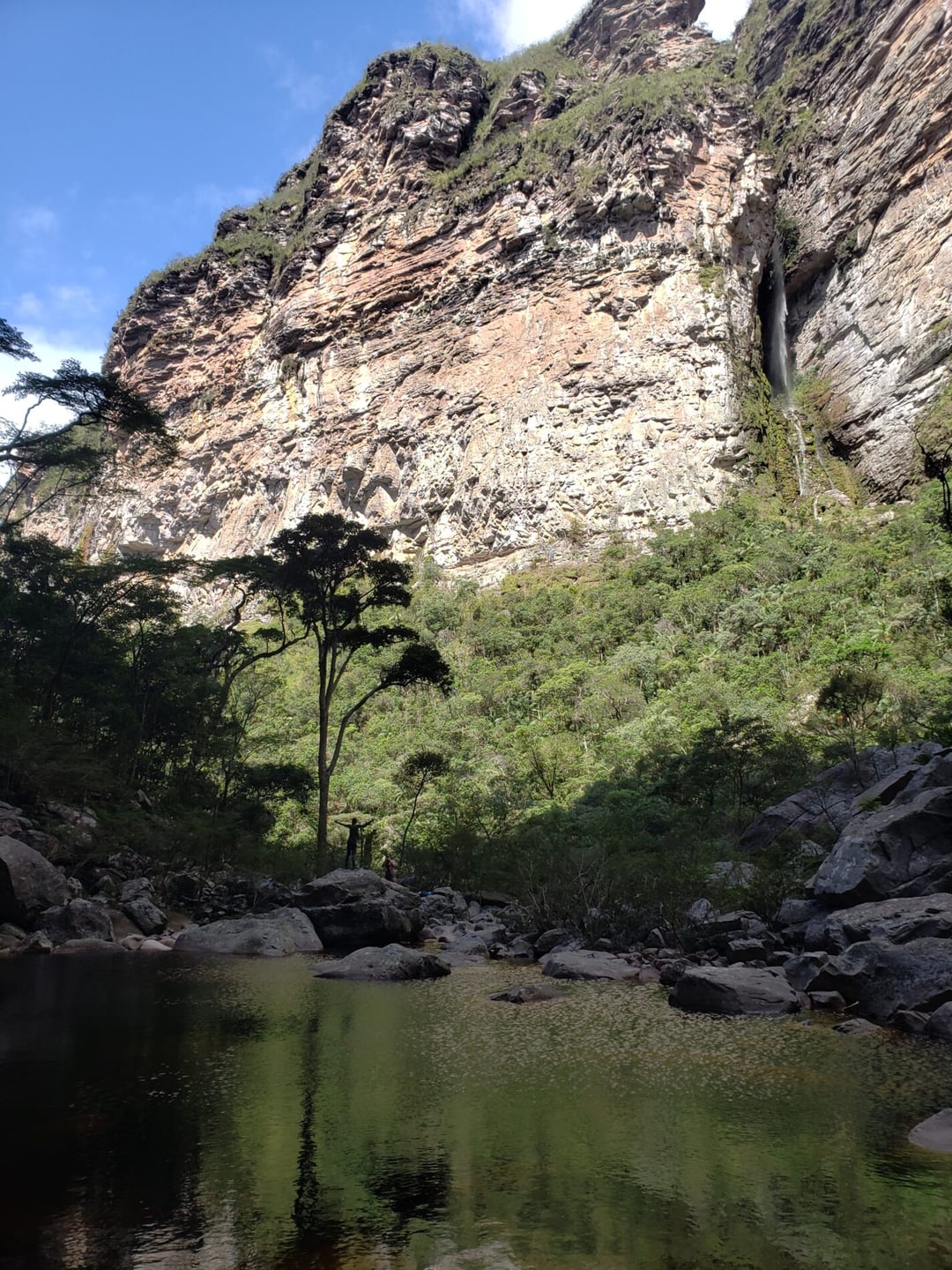 Excursionista de pie bajo la enorme cascada del Cachoeirão, en la Chapada Diamantina