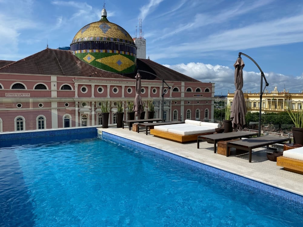 Rooftop swimming pool at Juma Ópera Hotel offering a direct view of the Amazon Theatre dome.