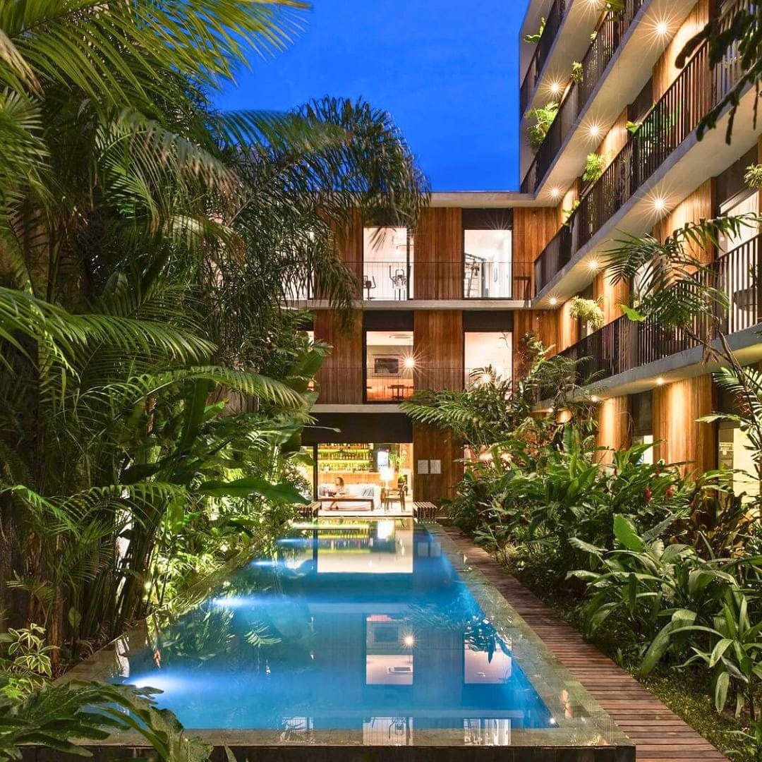Outdoor swimming pool surrounded by tropical gardens and building balconies at Hotel Villa Amazonia.