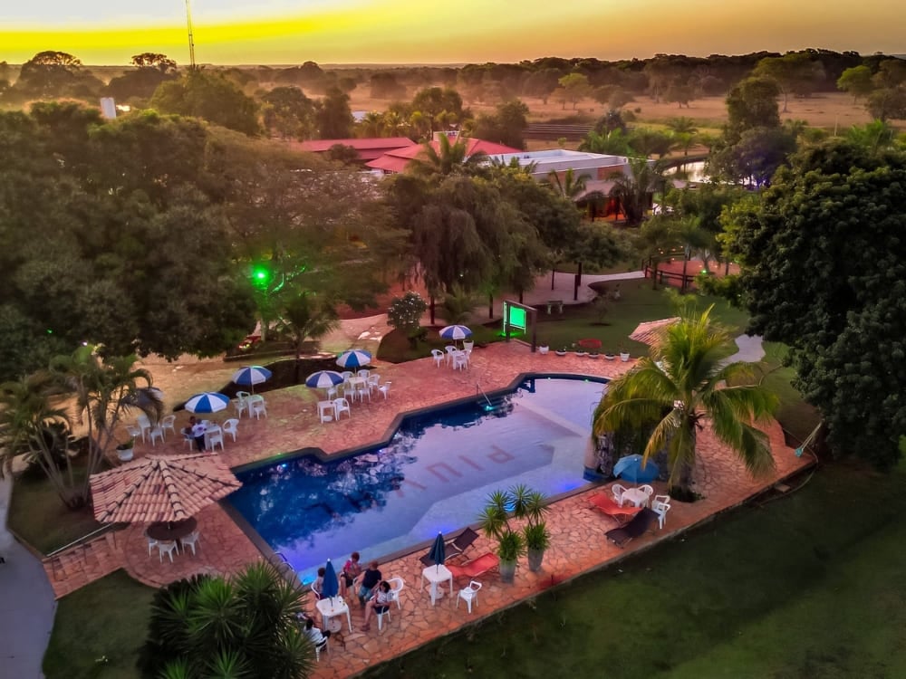 Des clients se détendent près de la piscine extérieure de l'auberge Piuval lors d'un coucher de soleil coloré dans le Pantanal Nord.