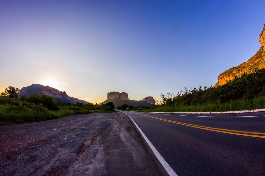Rodovia pavimentada vazia em direção às monthas da Chapada Diamantina, Bahia, ao nascer do sol.