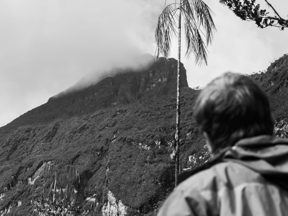 Um trilheiro olha em direção ao cume coberto de névoa do Pico da Neblina, o pico mais alto do Brasil.