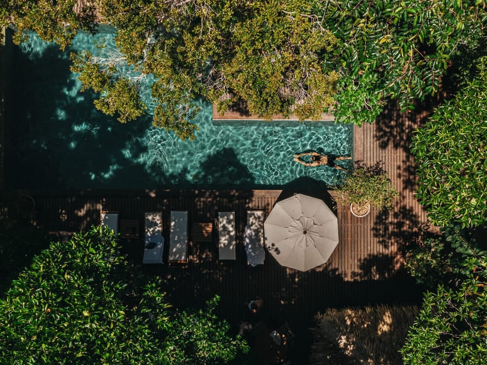 Vista aérea de um hotel de selva (lodge) na Amazônia com piscina e deck de madeira rodeado por árvores densas.