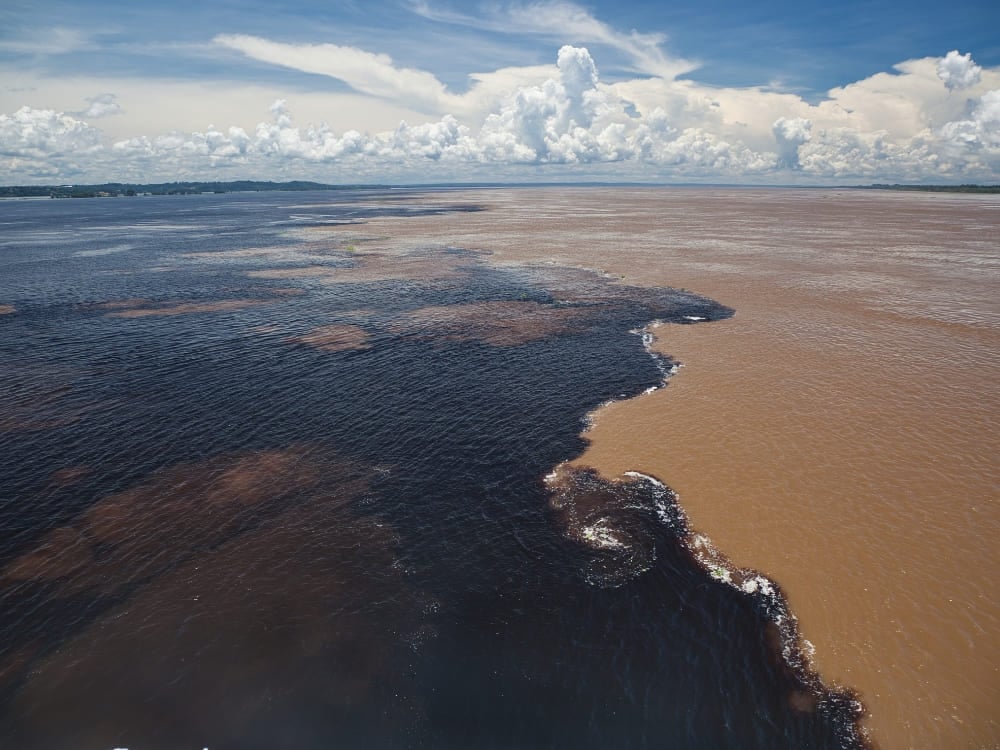 Vista aérea do Encontro das Águas, onde o escuro Rio Negro flui ao lado do barrento Rio Solimões sem se misturar.