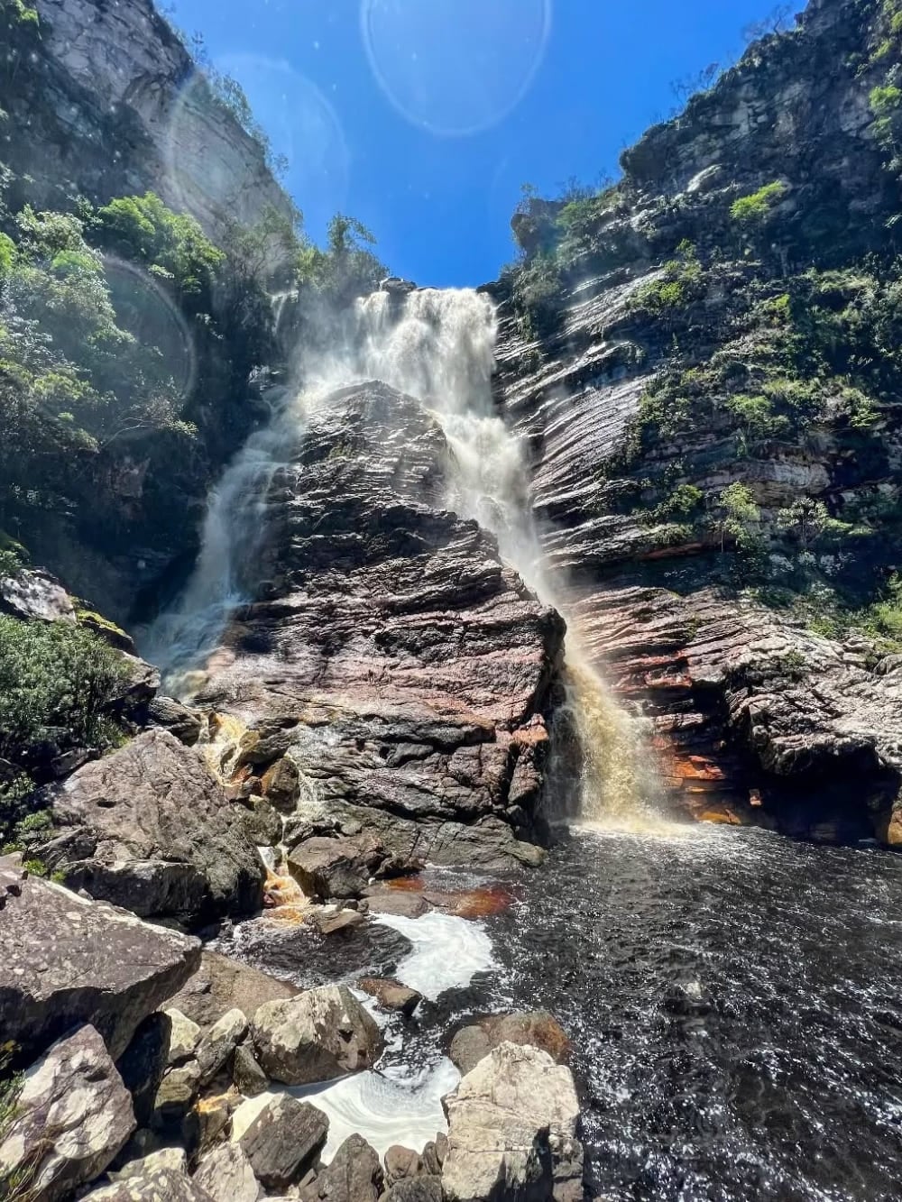 De hoge Samuel-waterval stroomt over massieve rotswanden naar beneden in een donkere poel, omgeven door weelderig bos in de buurt van Andaraí.