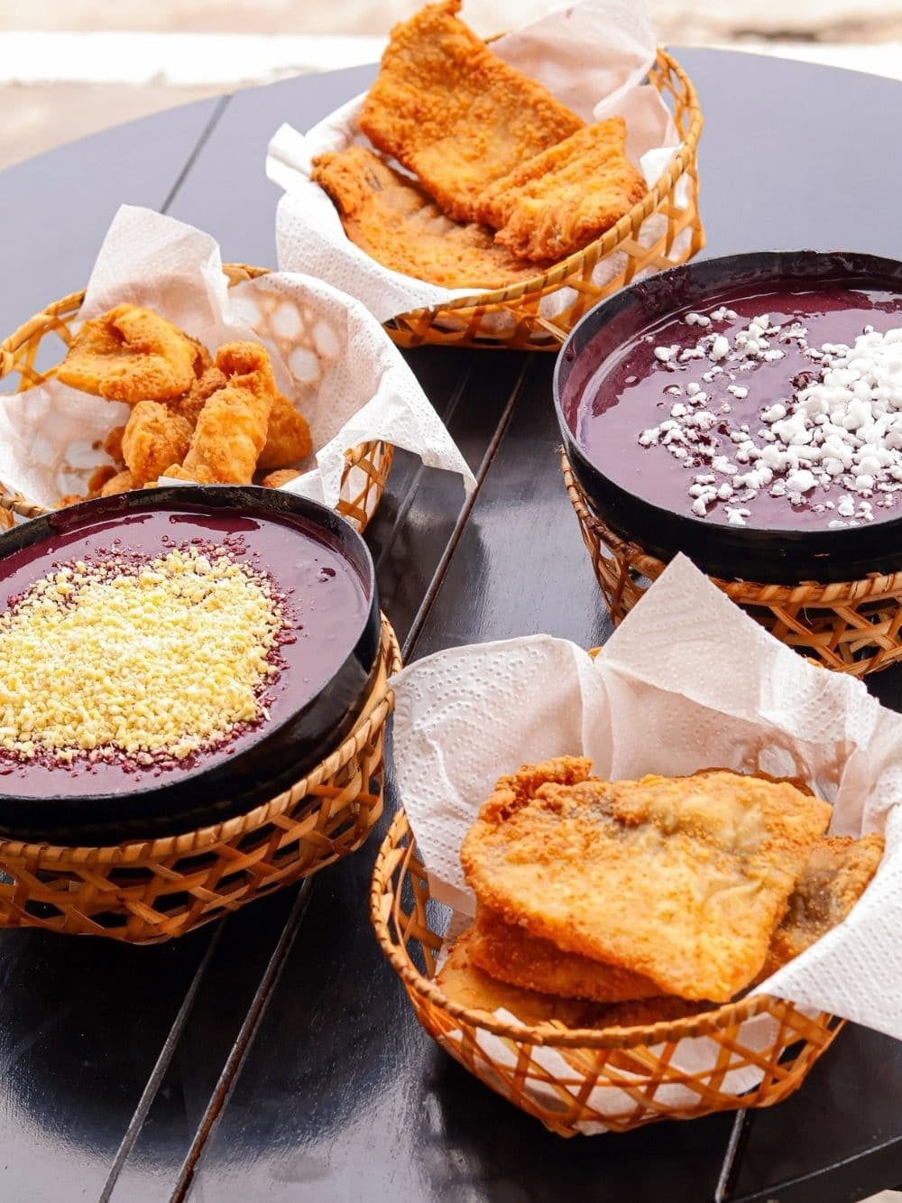 Bowls of thick unsweetened açaí topped with cassava flour, served with baskets of fried fish in Pará