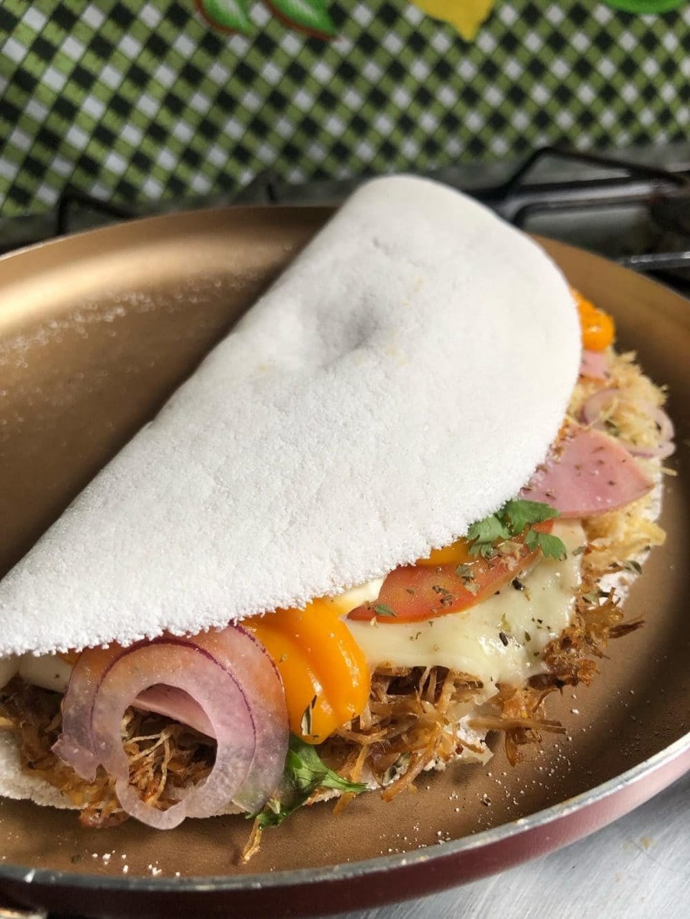 A folded tapioca crepe stuffed with melted cheese, shredded meat, tomato, onion and pimenta-de-cheiro