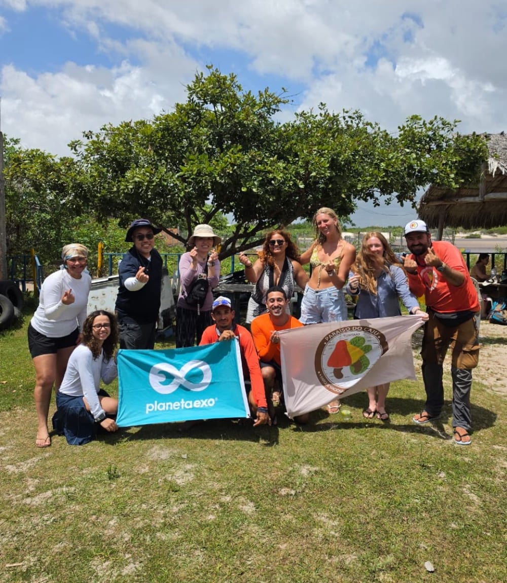 Il gruppo del trekking in posa con una bandiera di PlanetaEXO nei Lençóis Maranhenses