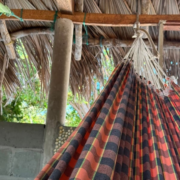 Gestreifte Hängematte unter einem Palmstrohdach, das typische Bett beim Trekking durch die Lençóis Maranhenses