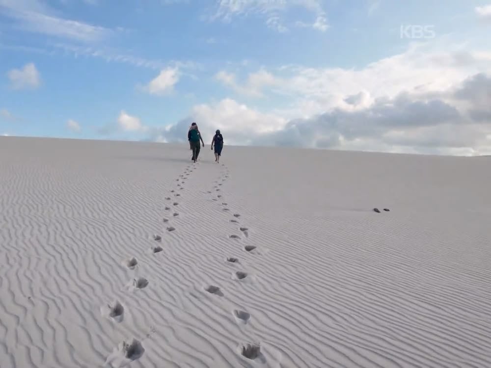 Due escursionisti salgono su una duna di sabbia increspata lasciando impronte nei Lençóis Maranhenses
