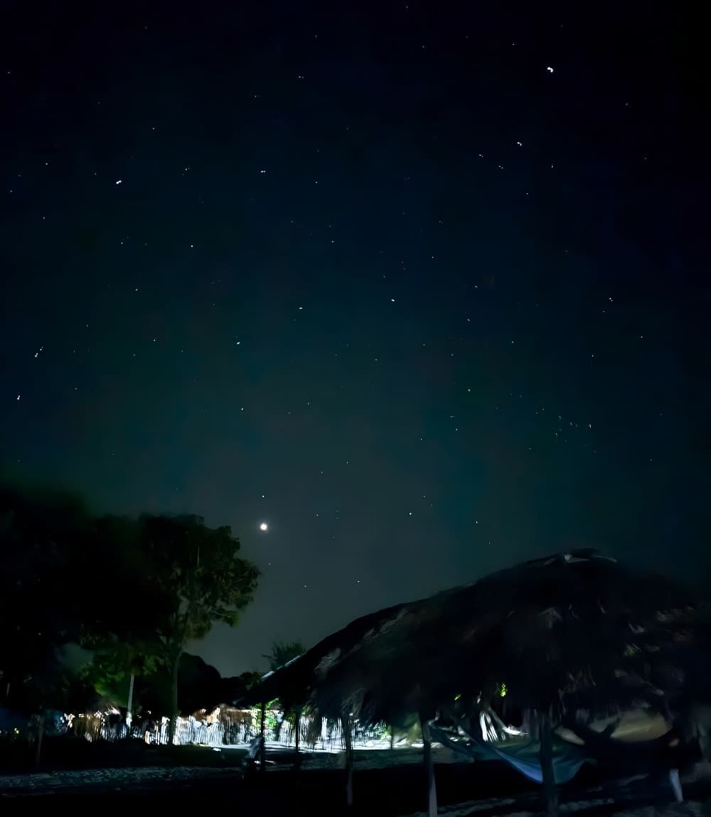 Cielo stellato sopra ripari di paglia e amache durante il trekking nei Lençóis Maranhenses
