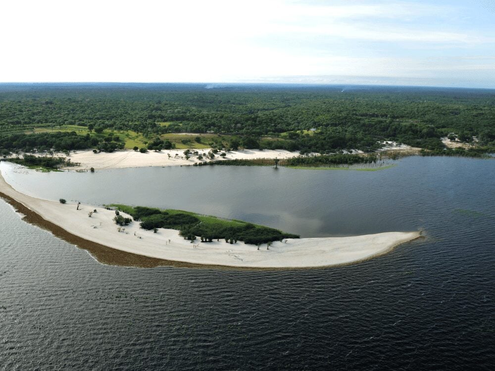 Vista aérea de praias de rio e bancos de areia branca em um rio de águas escuras cercado pela Floresta Amazônica na seca