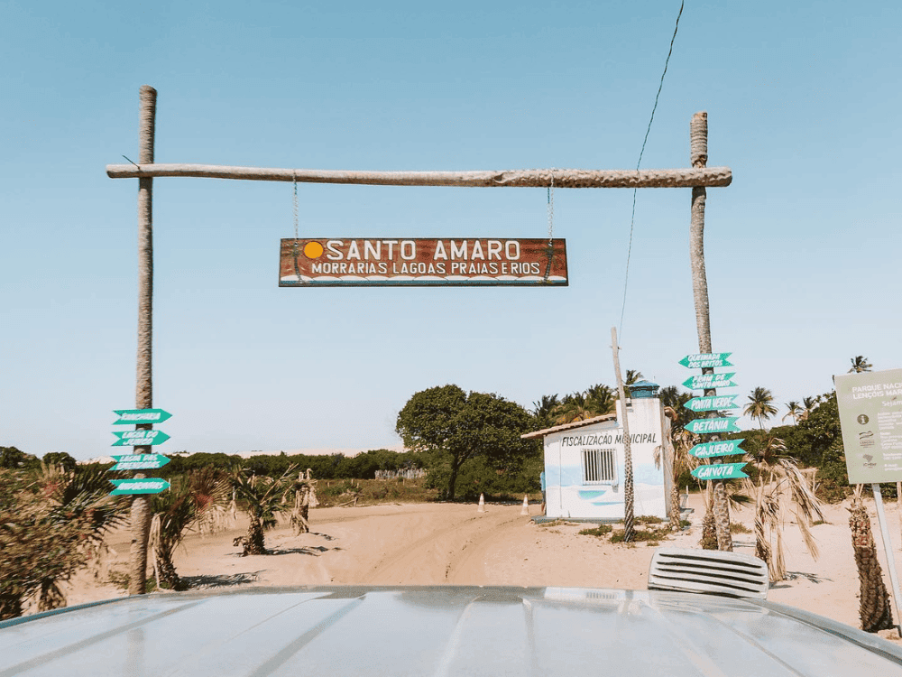 Rustieke toegangspoort met een houten bord met de tekst Santo Amaro boven een zanderige weg. Rustieke toegangspoort met een houten bord met de tekst Santo Amaro boven een zanderige weg.