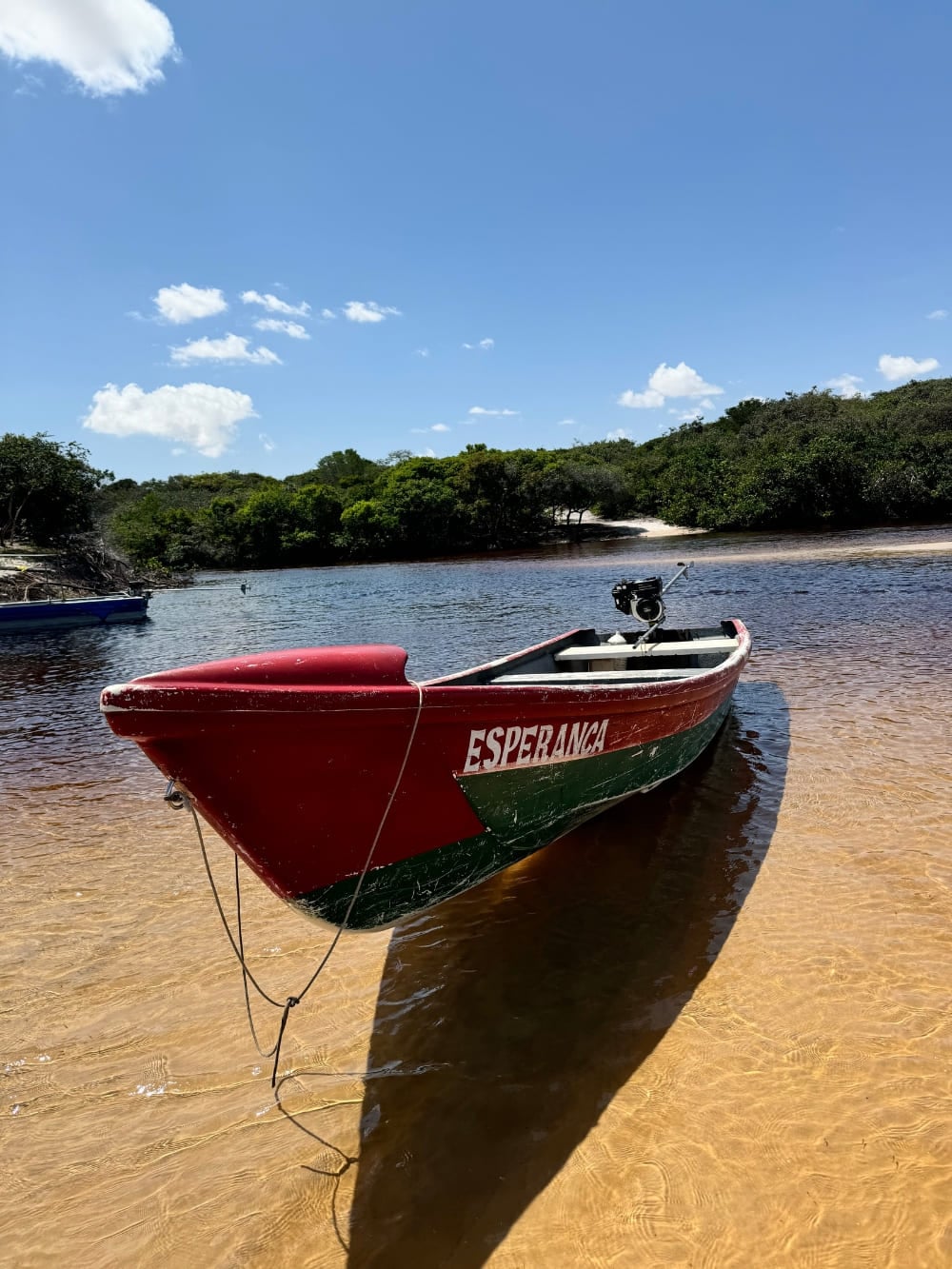 Um barco vermelho e verde chamado Esperança descansa na margem arenosa das águas escuras do Rio Preguiças. Um barco vermelho e verde chamado Esperança descansa na margem arenosa das águas escuras do Rio Preguiças.