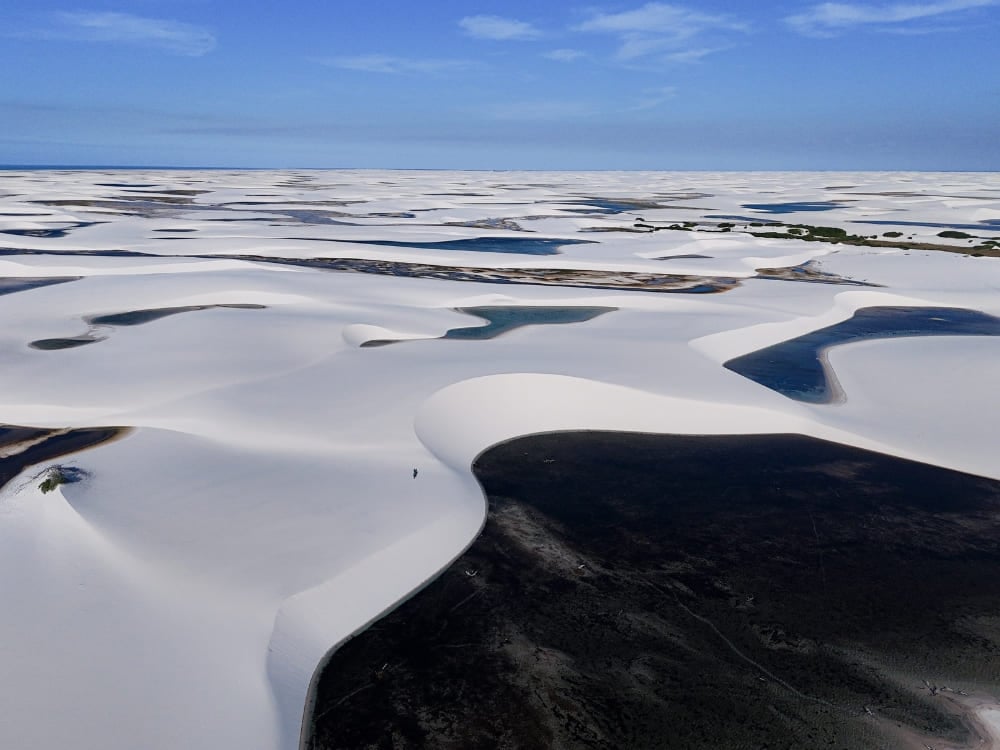 Uma ampla paisagem mostra milhares de lagoas de água da chuva intercaladas entre as dunas de areia branca. Uma ampla paisagem mostra milhares de lagoas de água da chuva intercaladas entre as dunas de areia branca.