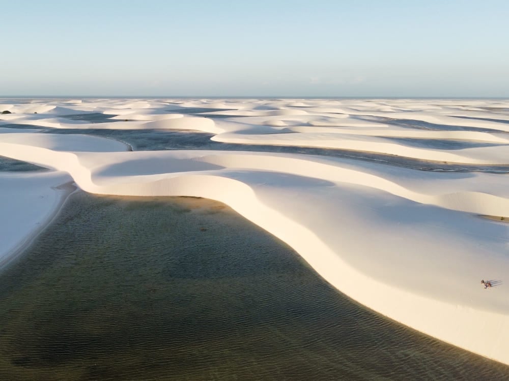 Vista aérea das dunas ativas de areia branca e lagoas de água da chuva nos Lençóis Maranhenses, estendendo-se em direção ao horizonte. Vista aérea das dunas ativas de areia branca e lagoas de água da chuva nos Lençóis Maranhenses, estendendo-se em direção ao horizonte.