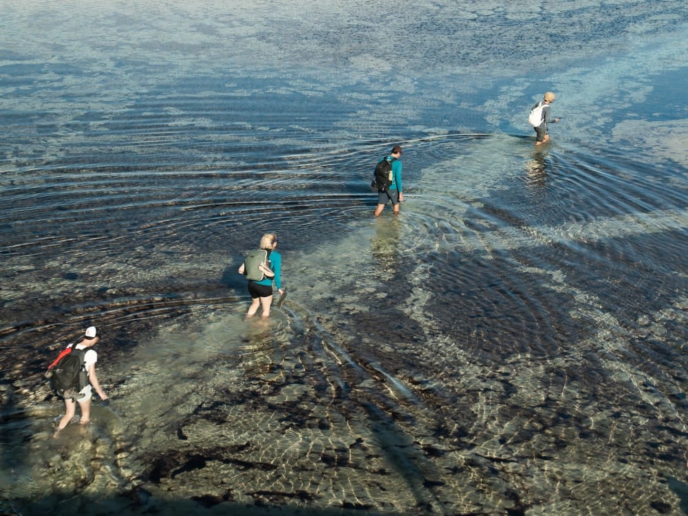 Um grupo guiado de viajantes caminhando por águas rasas nas infinitas dunas de areia em um passeio nos Lençóis Maranhenses. Um grupo guiado de viajantes caminhando por águas rasas nas infinitas dunas de areia em um passeio nos Lençóis Maranhenses.