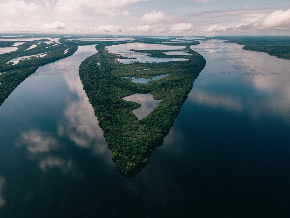Vista aérea deslumbrante de uma bifurcação de rio e ilhas verdes exuberantes na bacia amazônica, destacando a vasta hidrologia e beleza da região. Vista aérea deslumbrante de uma bifurcação de rio e ilhas verdes exuberantes na bacia amazônica, destacando a vasta hidrologia e beleza da região.