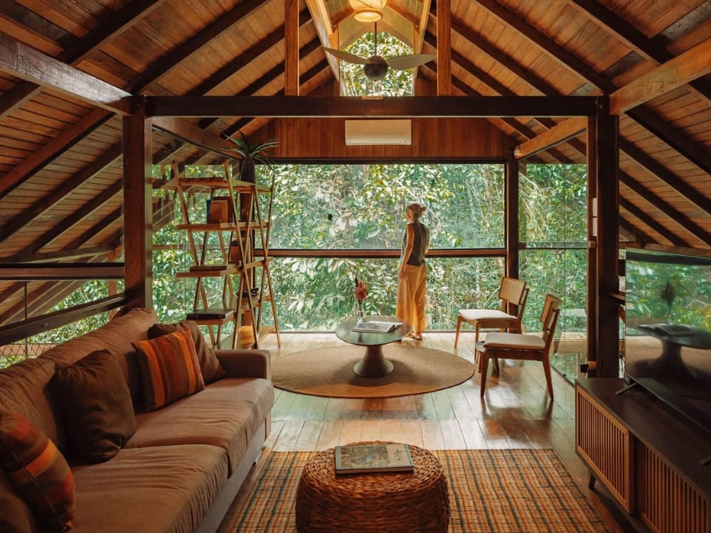 Área de estar aconchegante dentro de um hotel de selva na Amazônia com grandes janelas de vidro oferecendo vistas imersivas da floresta densa ao redor. Área de estar aconchegante dentro de um hotel de selva na Amazônia com grandes janelas de vidro oferecendo vistas imersivas da floresta densa ao redor.