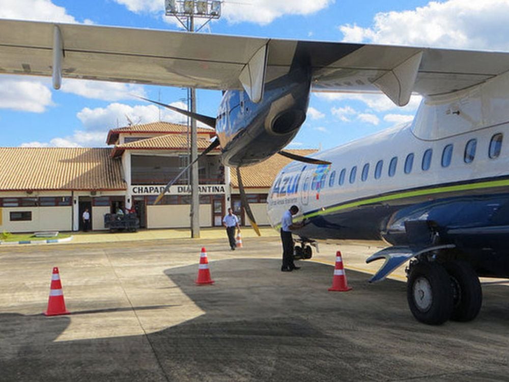 Avião da companhia aérea Azul estacionado na pista do aeroporto da Chapada Diamantina. Funcionários trabalham perto da aeronave em um dia ensolarado. Avião da companhia aérea Azul estacionado na pista do aeroporto da Chapada Diamantina. Funcionários trabalham perto da aeronave em um dia ensolarado.