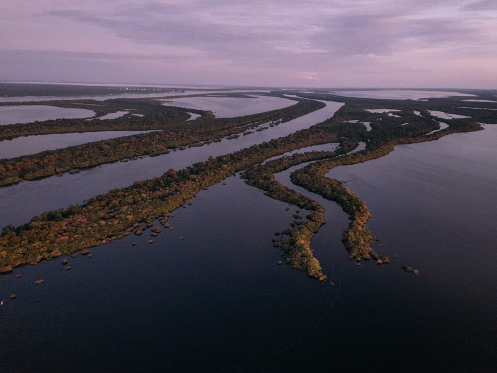Panorama aéreo dos canais do rio Amazonas e ilhas verdes exuberantes, destacando a enorme bacia hidrográfica e o ecossistema de água doce da região. Panorama aéreo dos canais do rio Amazonas e ilhas verdes exuberantes, destacando a enorme bacia hidrográfica e o ecossistema de água doce da região.