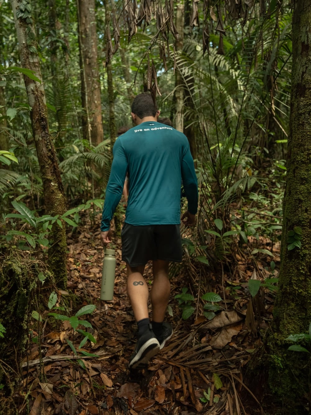 Un voyageur faisant de la randonnée sur un sentier forestier entouré de grands arbres en Amazonie, une activité typique de la saison sèche. Un voyageur faisant de la randonnée sur un sentier forestier entouré de grands arbres en Amazonie, une activité typique de la saison sèche.