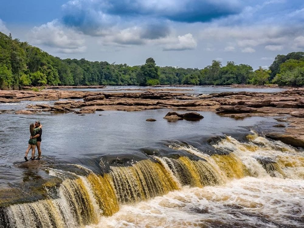 Ein Paar umarmt sich im flachen Wasser der Stromschnellen, umgeben von Wald im Jaú-Nationalpark. Ein Paar umarmt sich im flachen Wasser der Stromschnellen, umgeben von Wald im Jaú-Nationalpark.