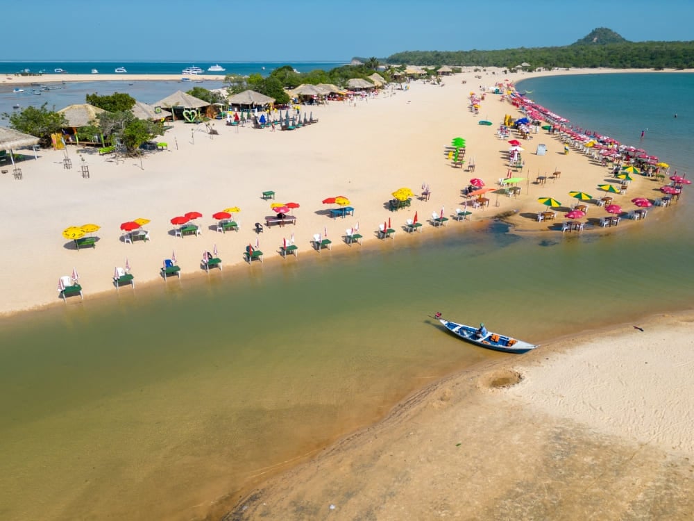 Weißer Sandstrand mit bunten Sonnenschirmen am grünlichen Wasser des Tapajós-Flusses in Alter do Chão. Weißer Sandstrand mit bunten Sonnenschirmen am grünlichen Wasser des Tapajós-Flusses in Alter do Chão.