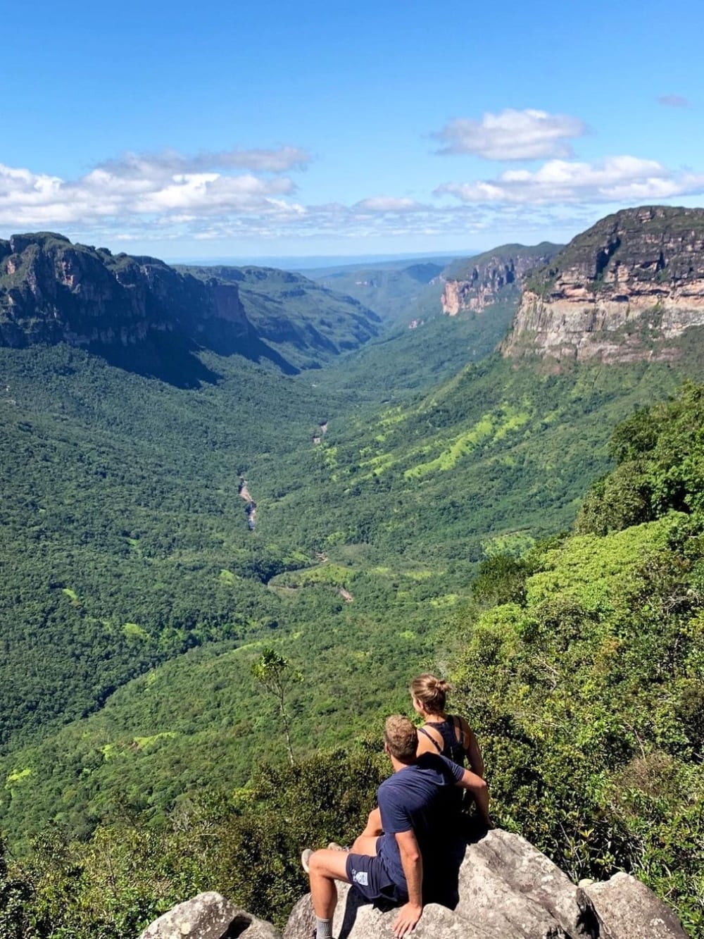 Dois trilheiros sentados em um penhasco rochoso admirando a vasta imensidão verde do Vale do Pati, no Parque Nacional da Chapada Diamantina. Dois trilheiros sentados em um penhasco rochoso admirando a vasta imensidão verde do Vale do Pati, no Parque Nacional da Chapada Diamantina.