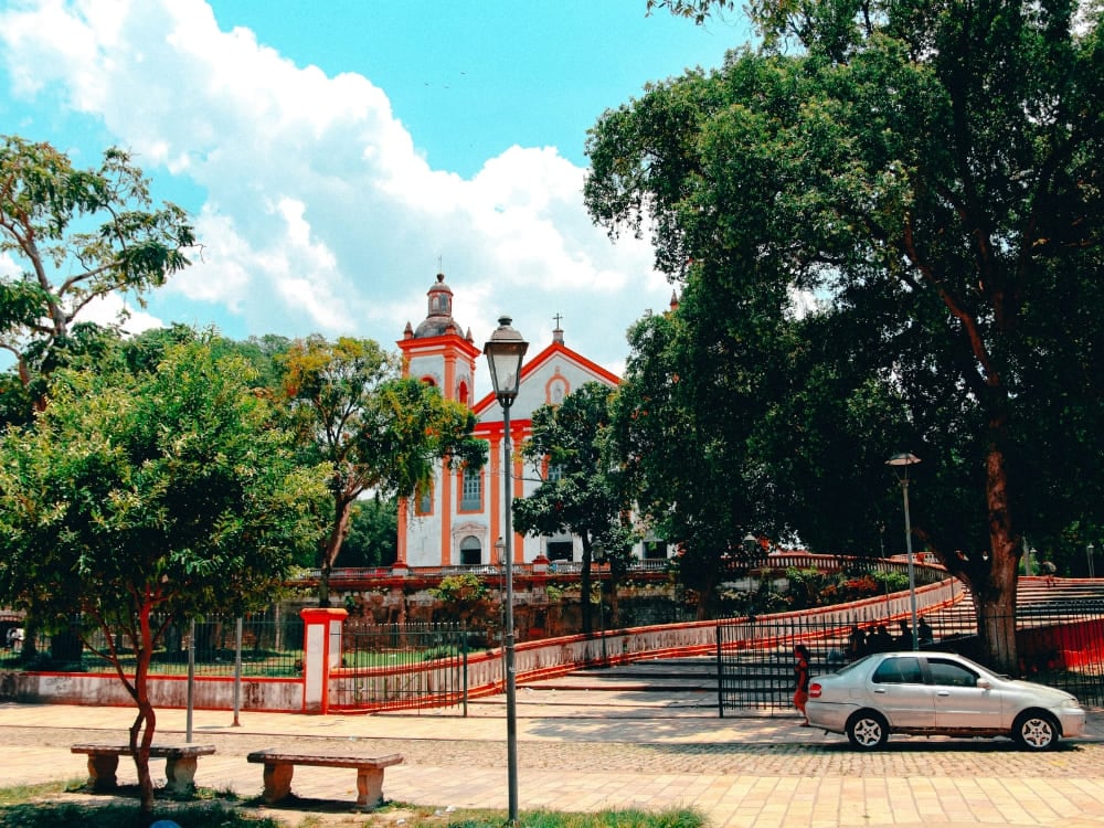 Eine weiße und orangefarbene historische Kirche mit geschwungener Rampe, umgeben von grünen Bäumen auf einem ruhigen Platz in Manaus. Eine weiße und orangefarbene historische Kirche mit geschwungener Rampe, umgeben von grünen Bäumen auf einem ruhigen Platz in Manaus.