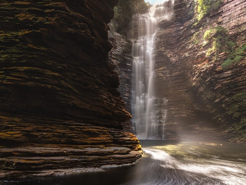 A Cachoeira do Buracão despenca 85 metros dentro de um cânion rochoso estreito com paredes em camadas, terminando em um poço natural escuro. A Cachoeira do Buracão despenca 85 metros dentro de um cânion rochoso estreito com paredes em camadas, terminando em um poço natural escuro.