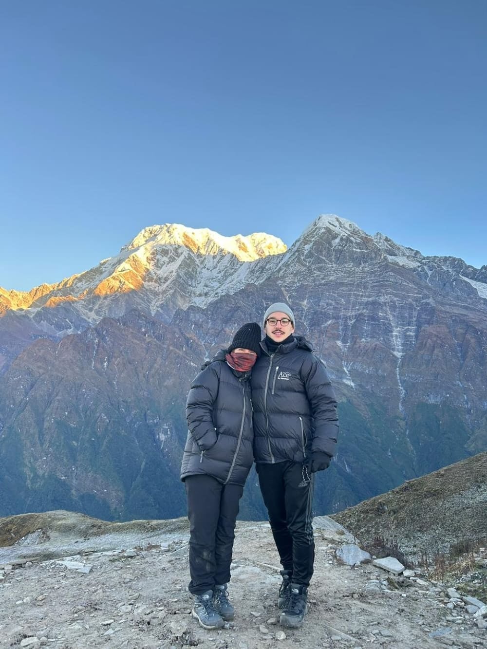 Moeder en zoon Mila en Lorenzo dragen zware winterkleding en omhelzen elkaar voor de besneeuwde toppen van de Himalaya na een vroege ochtendklim. Moeder en zoon Mila en Lorenzo dragen zware winterkleding en omhelzen elkaar voor de besneeuwde toppen van de Himalaya na een vroege ochtendklim.