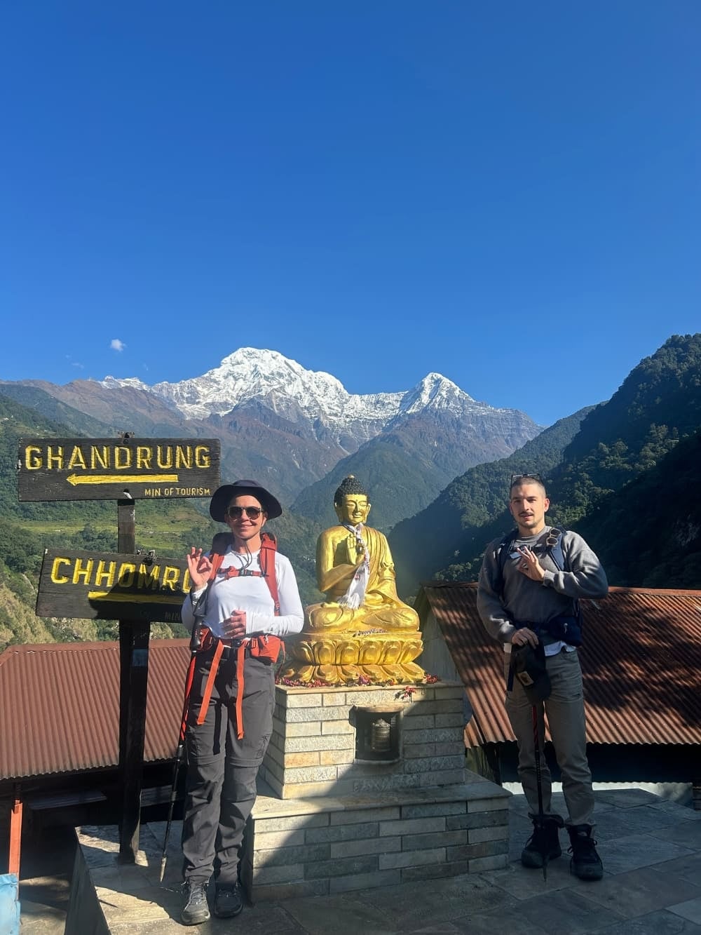 Mila en Lorenzo naast een Boeddhabeeld en routeborden tijdens hun duurzame trektocht in Nepal. Mila en Lorenzo naast een Boeddhabeeld en routeborden tijdens hun duurzame trektocht in Nepal.
