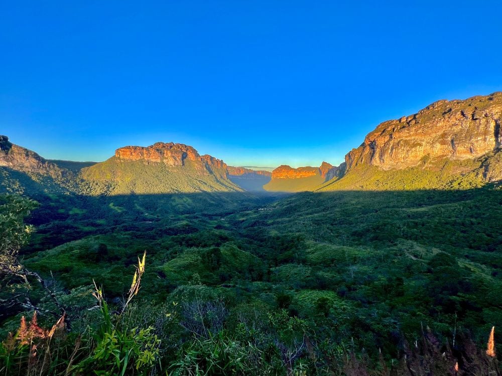 Panoramisch uitzicht op de uitgestrekte vallei en groene bergen verlicht door de zon onder een blauwe lucht in Nationaal Park Chapada Diamantina. Panoramisch uitzicht op de uitgestrekte vallei en groene bergen verlicht door de zon onder een blauwe lucht in Nationaal Park Chapada Diamantina.
