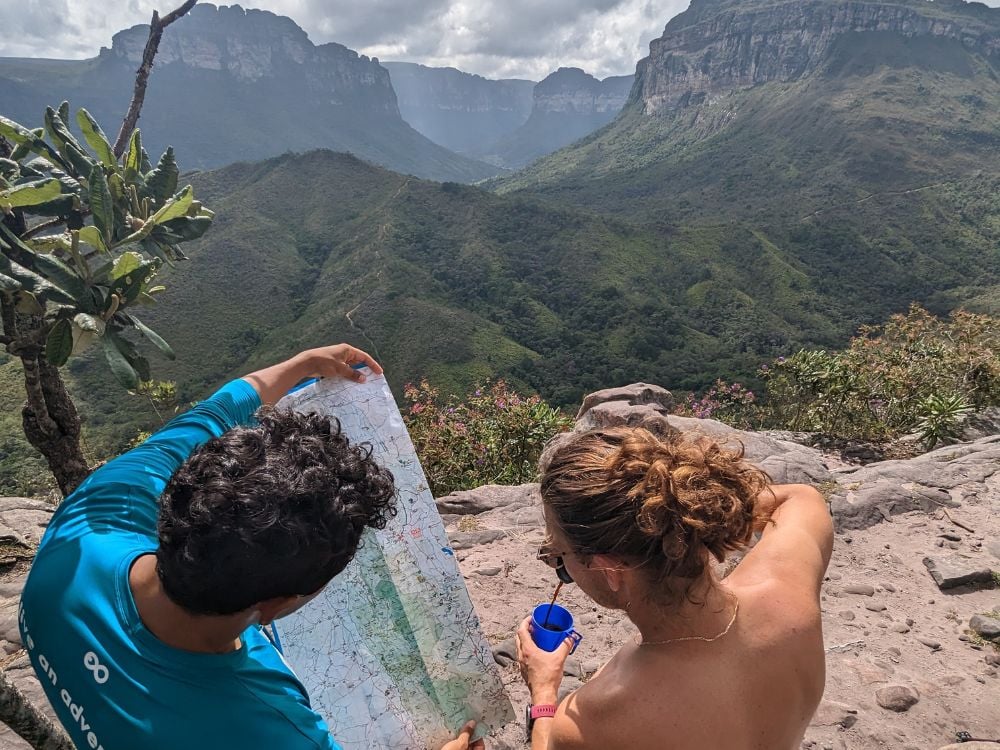 Reisgids in een blauw shirt en een toerist die samen een routekaart bestuderen bij een bergachtig uitkijkpunt in Nationaal Park Chapada Diamantina. Reisgids in een blauw shirt en een toerist die samen een routekaart bestuderen bij een bergachtig uitkijkpunt in Nationaal Park Chapada Diamantina.