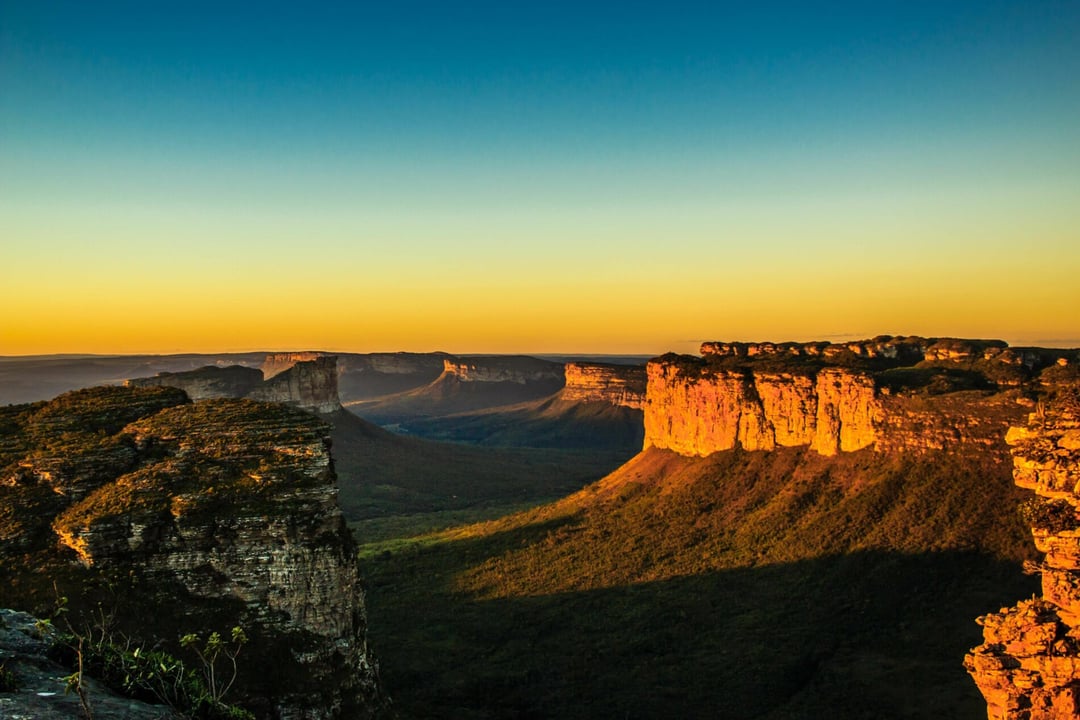 Panoramablick auf die Tafelberge der Chapada Diamantina und die tiefgrünen Täler, die vom goldenen Licht eines Sonnenuntergangs beleuchtet werden. Panoramablick auf die Tafelberge der Chapada Diamantina und die tiefgrünen Täler, die vom goldenen Licht eines Sonnenuntergangs beleuchtet werden.