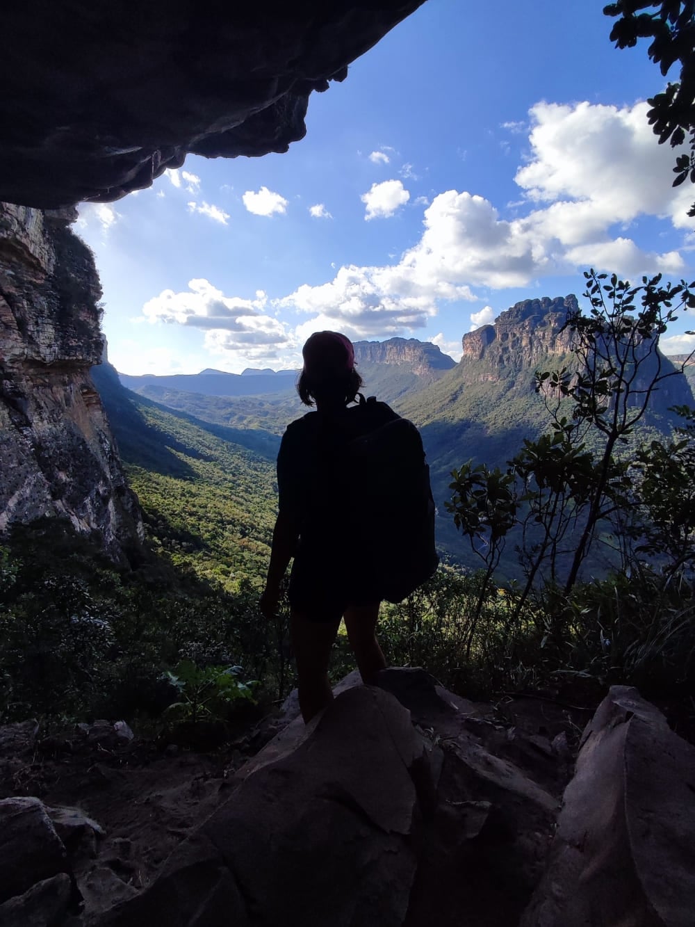 Silhueta de um trilheiro com mochila em pé na entrada escura de uma caverna, olhando para o ensolarado Vale do Pati. Silhueta de um trilheiro com mochila em pé na entrada escura de uma caverna, olhando para o ensolarado Vale do Pati.