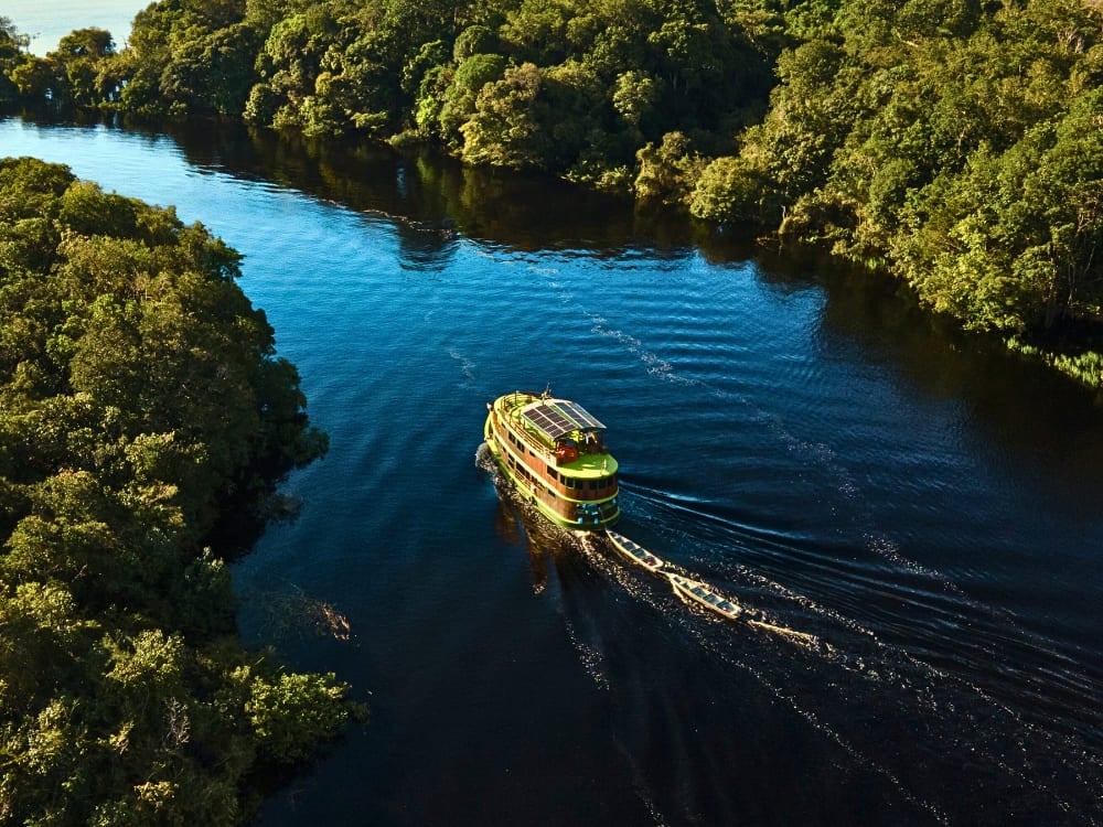 Barco de cruzeiro fluvial de vários andares na Amazônia atracado em uma praia de areia branca ao longo das águas escuras do rio. Barco de cruzeiro fluvial de vários andares na Amazônia atracado em uma praia de areia branca ao longo das águas escuras do rio.