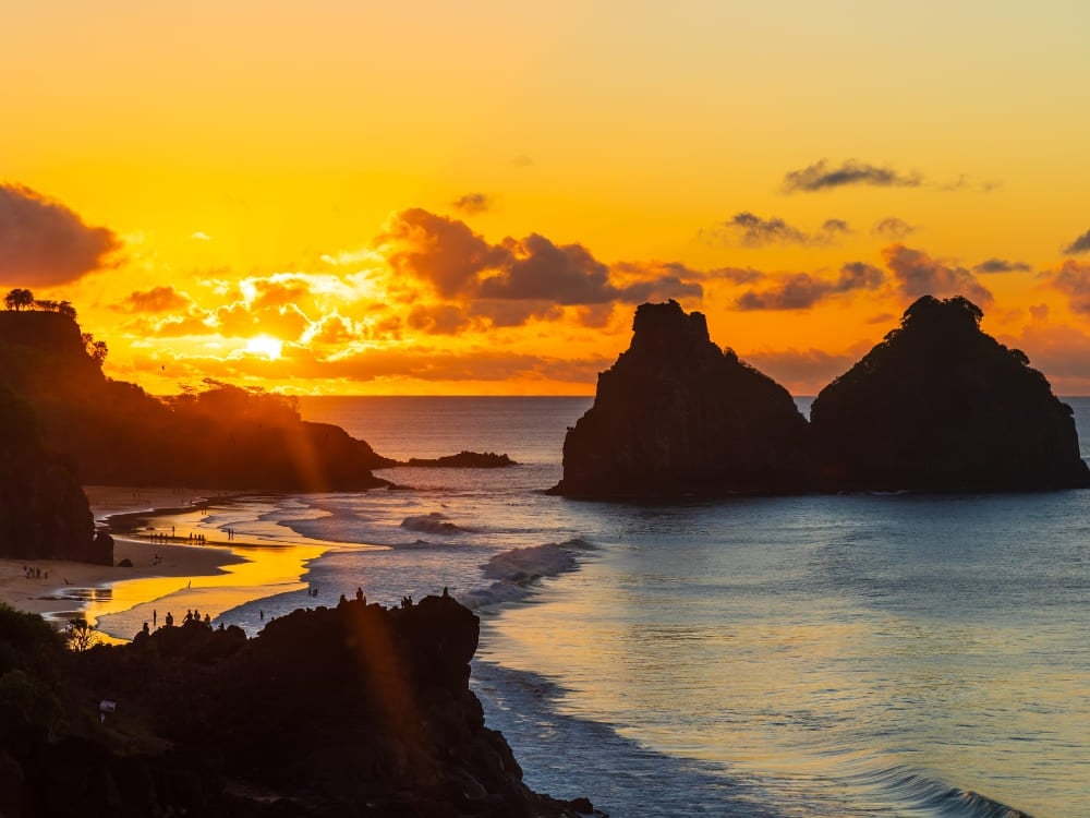 Golden sunset over the Morro Dois Irmaos rock formations, a famous landscape near hotels in Fernando de Noronha. Golden sunset over the Morro Dois Irmaos rock formations, a famous landscape near hotels in Fernando de Noronha.