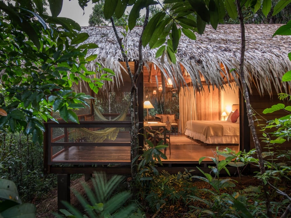 Um bangalô refinado com teto de palha e rede na varanda no Anavilhanas Jungle Lodge, no Brasil. Um bangalô refinado com teto de palha e rede na varanda no Anavilhanas Jungle Lodge, no Brasil.