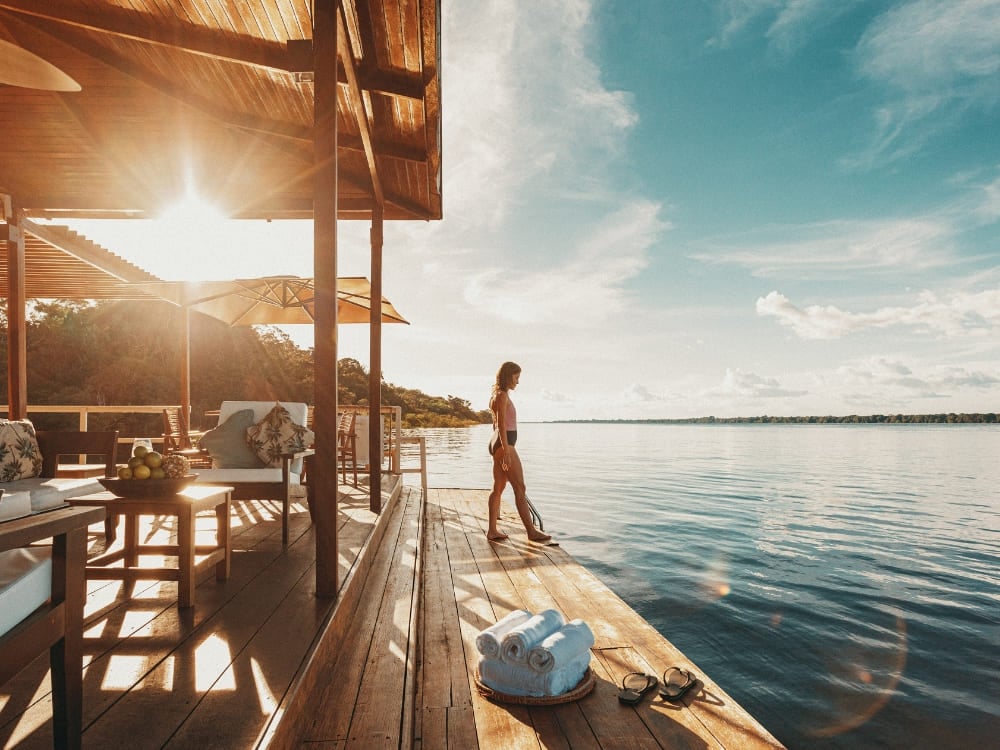 Uma mulher relaxa em um deck flutuante de madeira sobre o rio no Anavilhanas Jungle Lodge, um dos melhores lodges da Amazônia no Brasil. Uma mulher relaxa em um deck flutuante de madeira sobre o rio no Anavilhanas Jungle Lodge, um dos melhores lodges da Amazônia no Brasil.