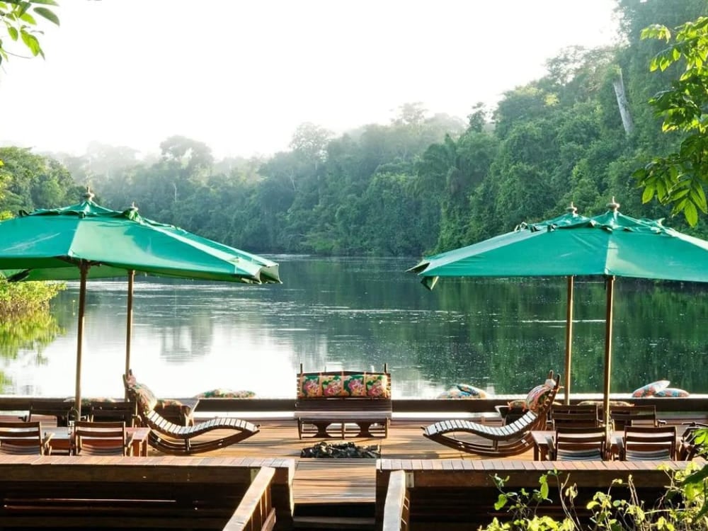 Espreguiçadeiras e guarda-sóis verdes no deck flutuante do Cristalino Lodge, um incrível eco lodge na Amazônia brasileira. Espreguiçadeiras e guarda-sóis verdes no deck flutuante do Cristalino Lodge, um incrível eco lodge na Amazônia brasileira.