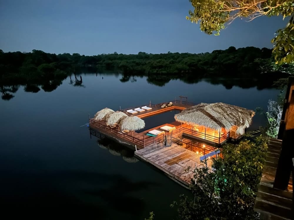 Um deck flutuante e piscina iluminados à noite no Juma Amazon Lodge, na floresta amazônica. Um deck flutuante e piscina iluminados à noite no Juma Amazon Lodge, na floresta amazônica.