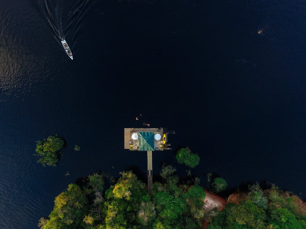 Prise de vue aérienne par drone d'un écolodge construit sur pilotis, entouré par les eaux sombres du fleuve Amazone et une jungle luxuriante. Prise de vue aérienne par drone d'un écolodge construit sur pilotis, entouré par les eaux sombres du fleuve Amazone et une jungle luxuriante.